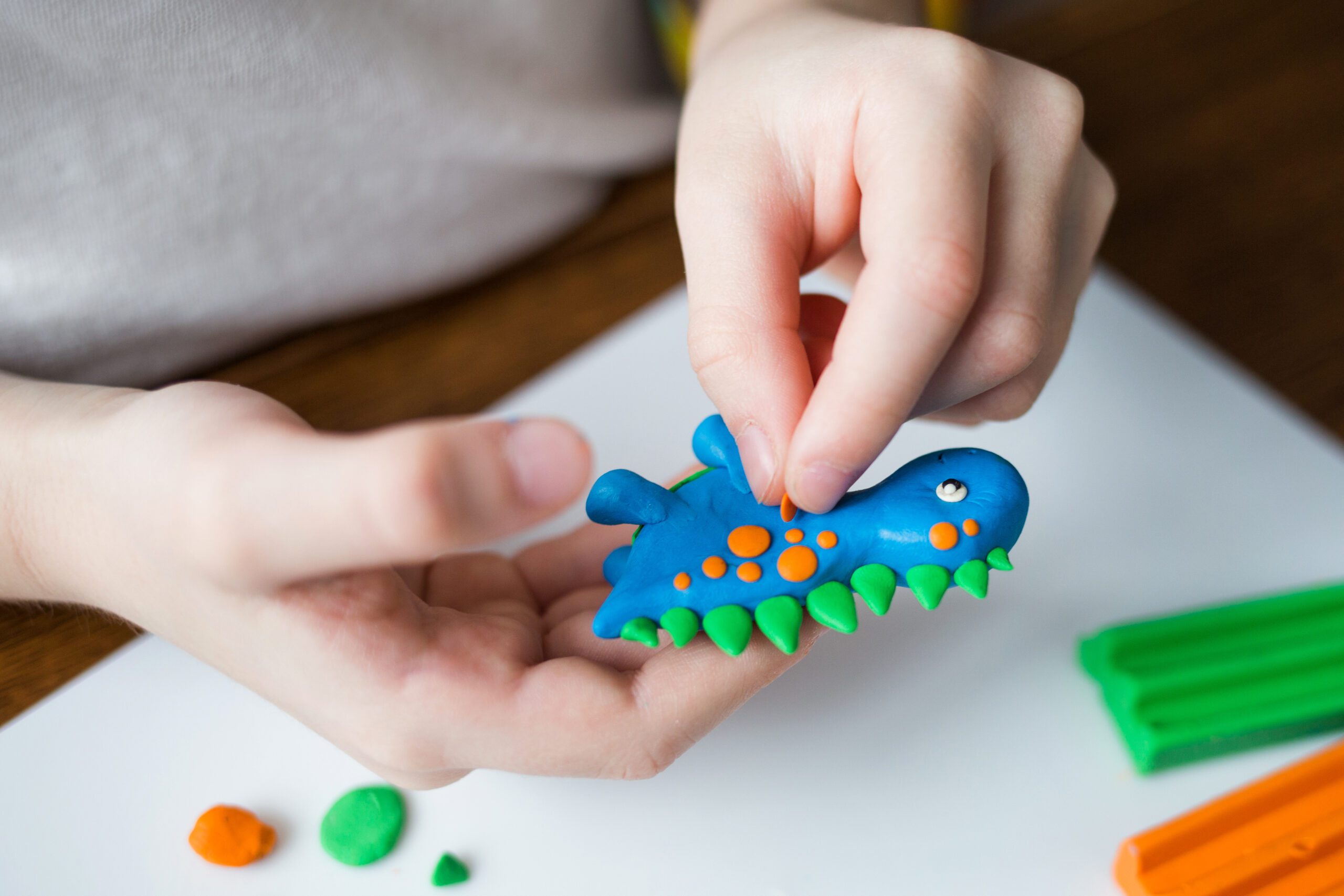 Creative kid molding at home. child play with plasticine. child sculpts a dinosaur