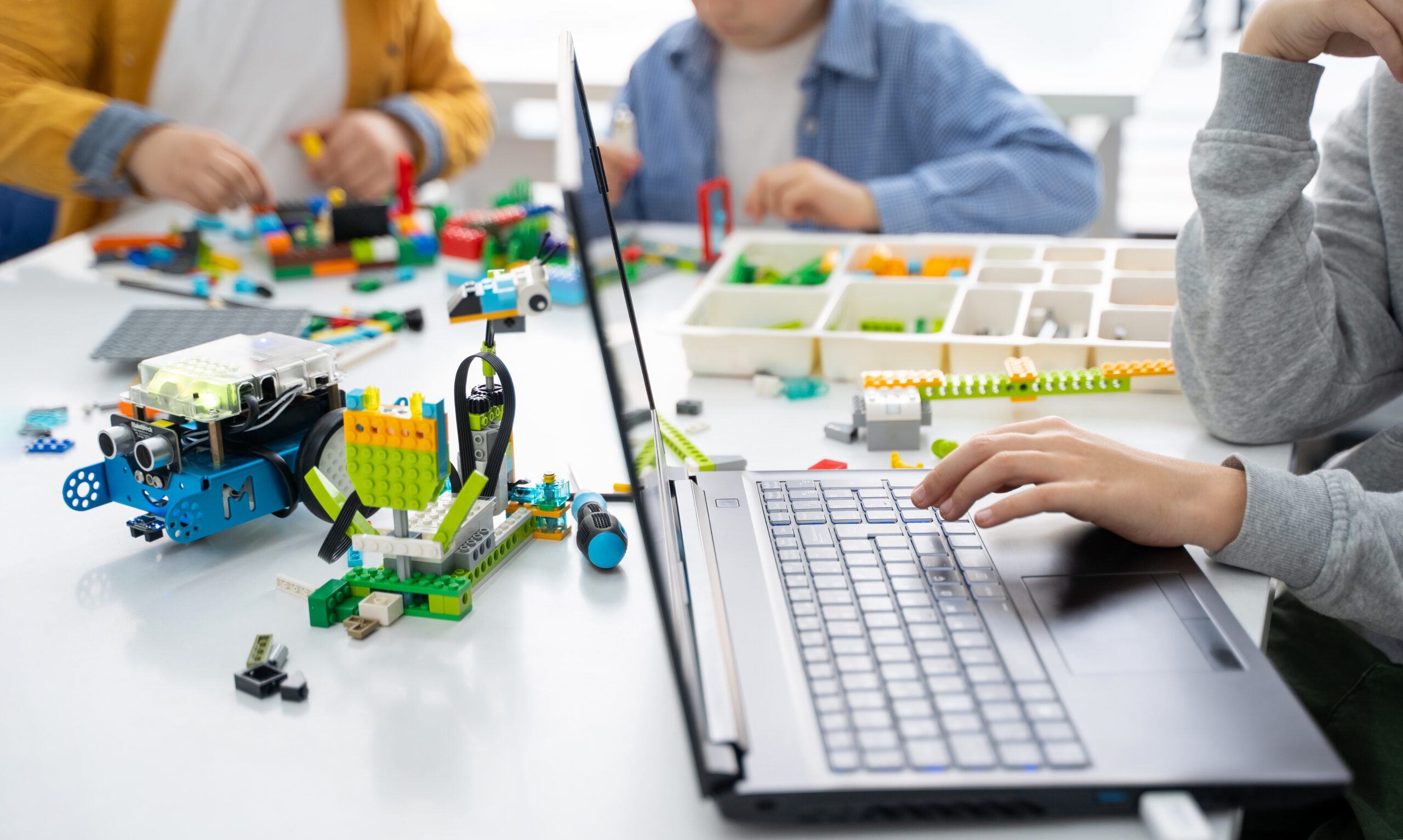 Robotics lego programming class. Children construct and code Robot Lego. STEM education using constructor blocks and laptop, remote control joystick. Technology educational development for school kids. Advertisement copy space