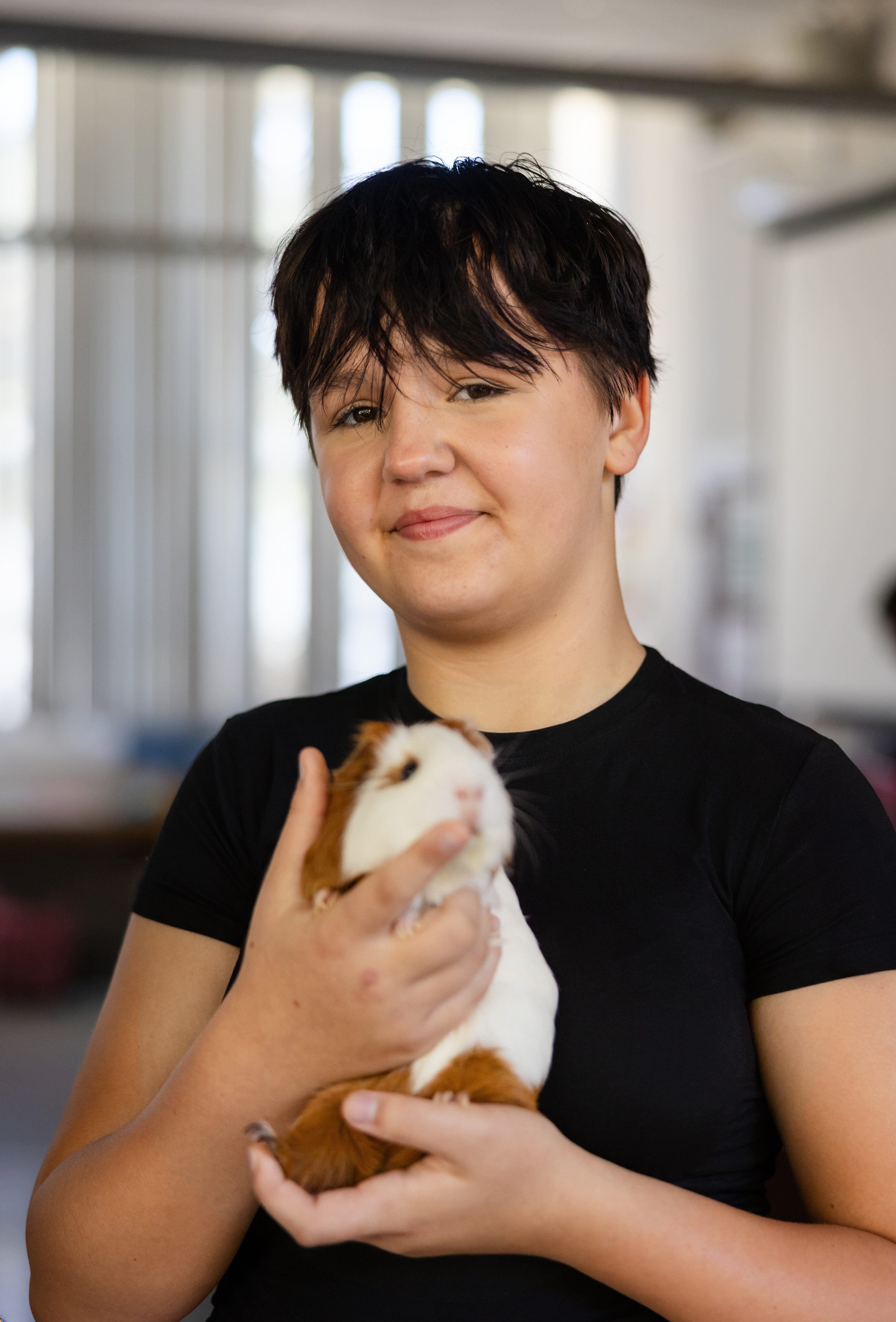 Hanna Center student smiling while holding a guinea pig on campus.
