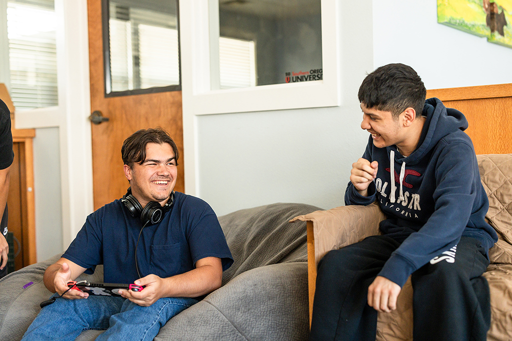 Two young men talking on a couch.