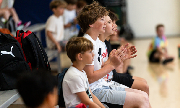 Kids cheering on the sideline in the Hanna Center gymnasium.