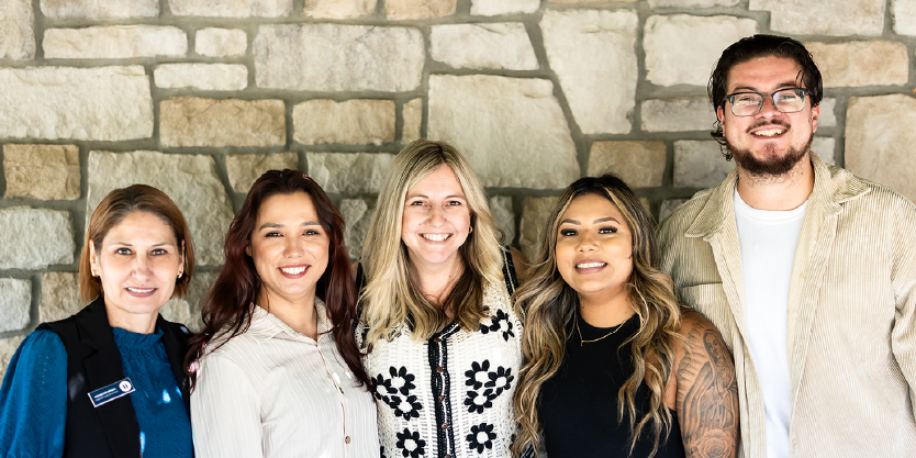 Group of five team members smiling for a photo.