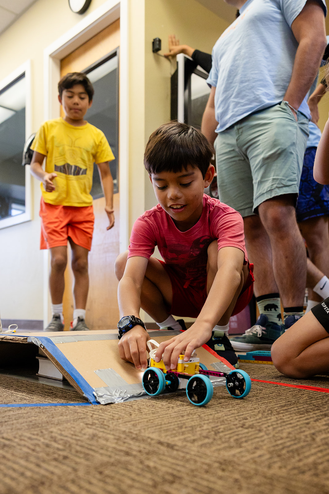 Camper tests a LEGO vehicle on a handmade ramp during a STEM activity at Hanna Center.