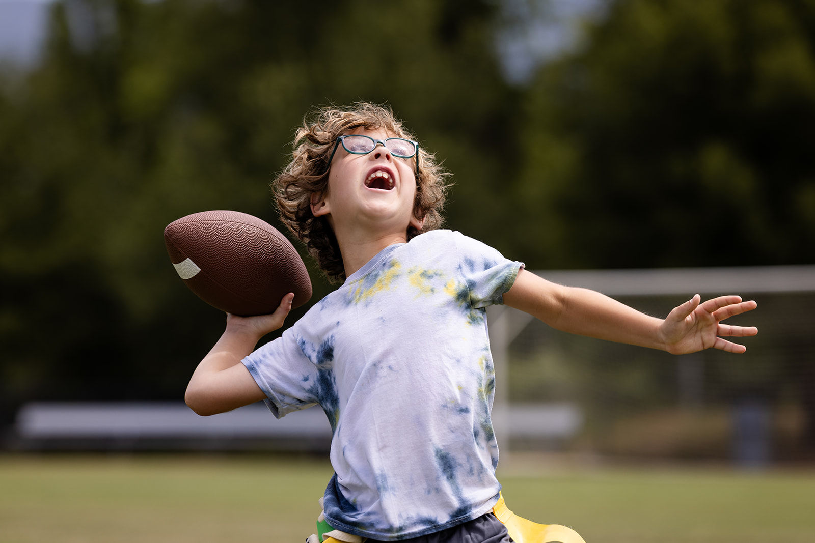 Camper holds a football and prepares to throw during outdoor recreation at Hanna Center.